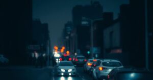 A dark cityscape at night with blurred lights and a somber atmosphere.